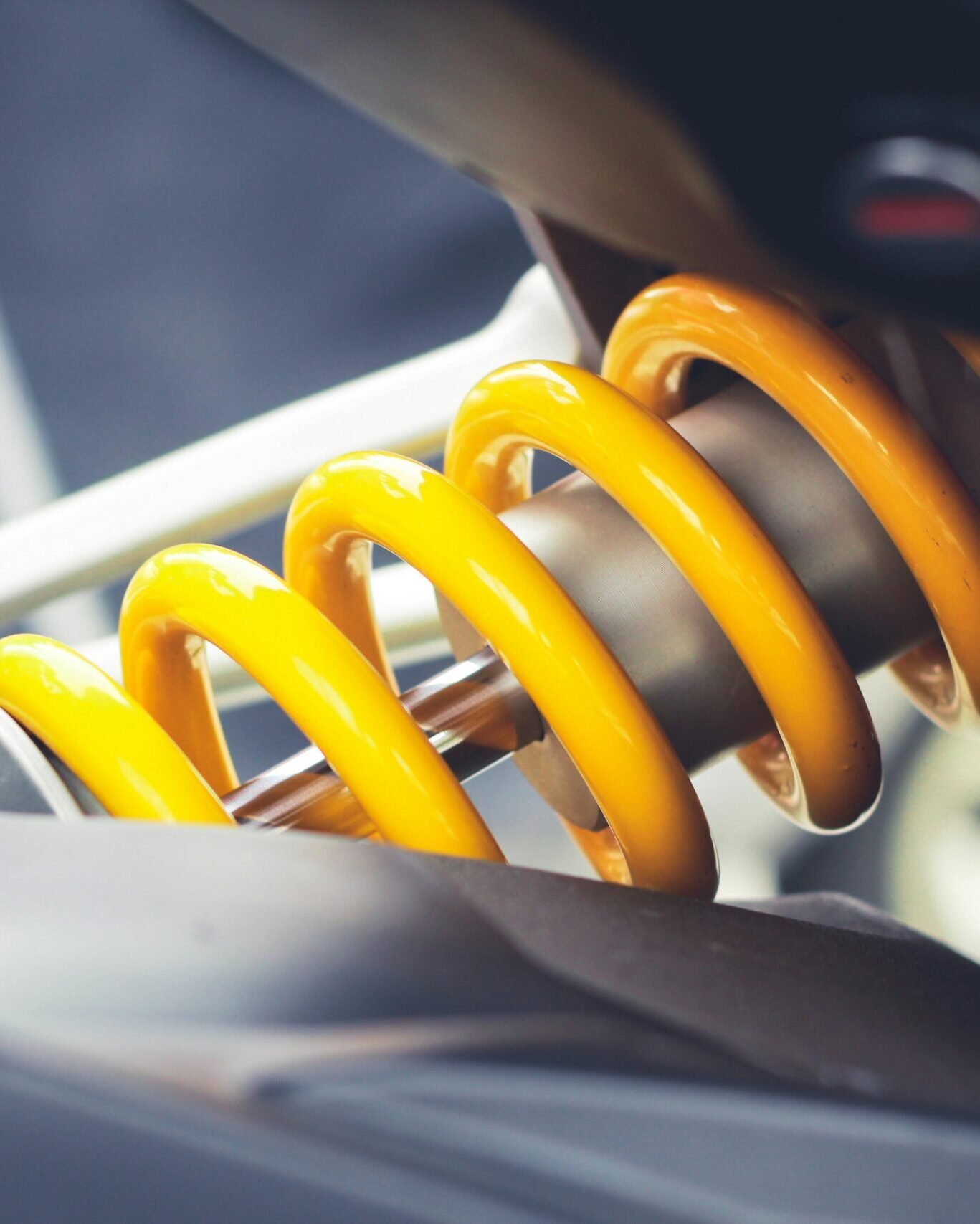 Close-up of a vibrant yellow coil spring, showcasing mechanical engineering details.