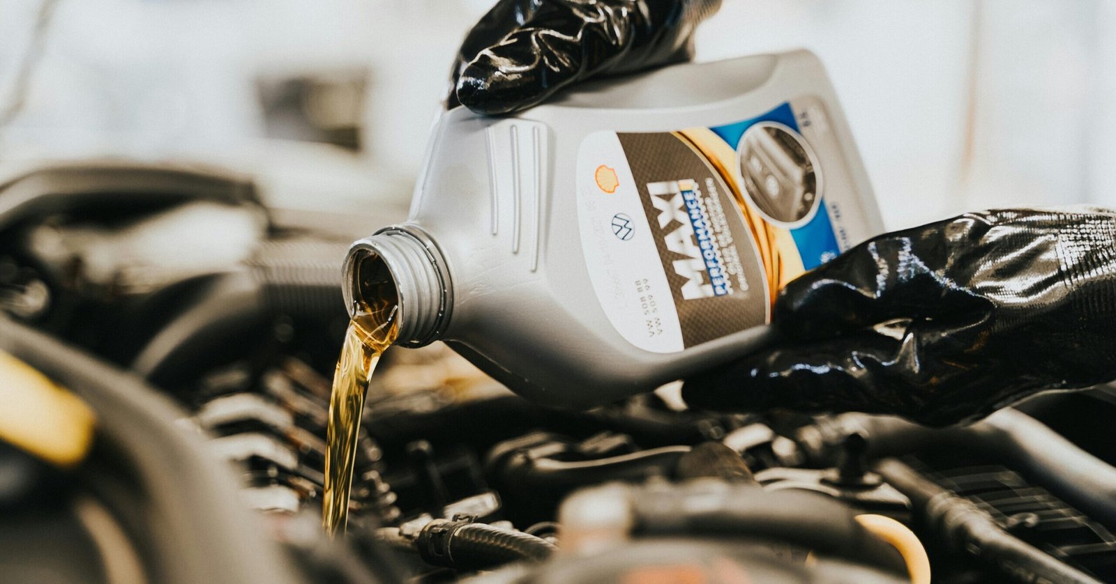 Close-up of a mechanic pouring engine oil into a car engine, highlighting maintenance work.